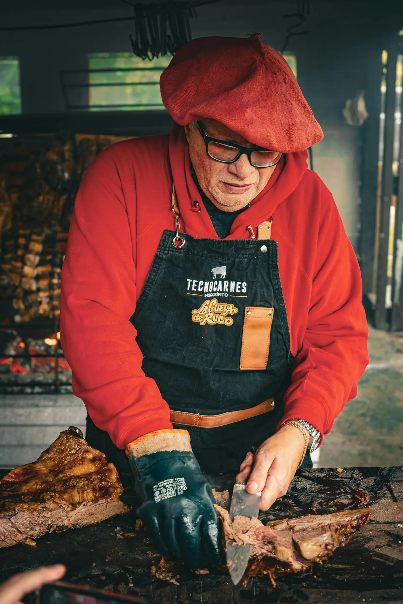 Argentine chef cutting grilled meat at an outdoor catering event