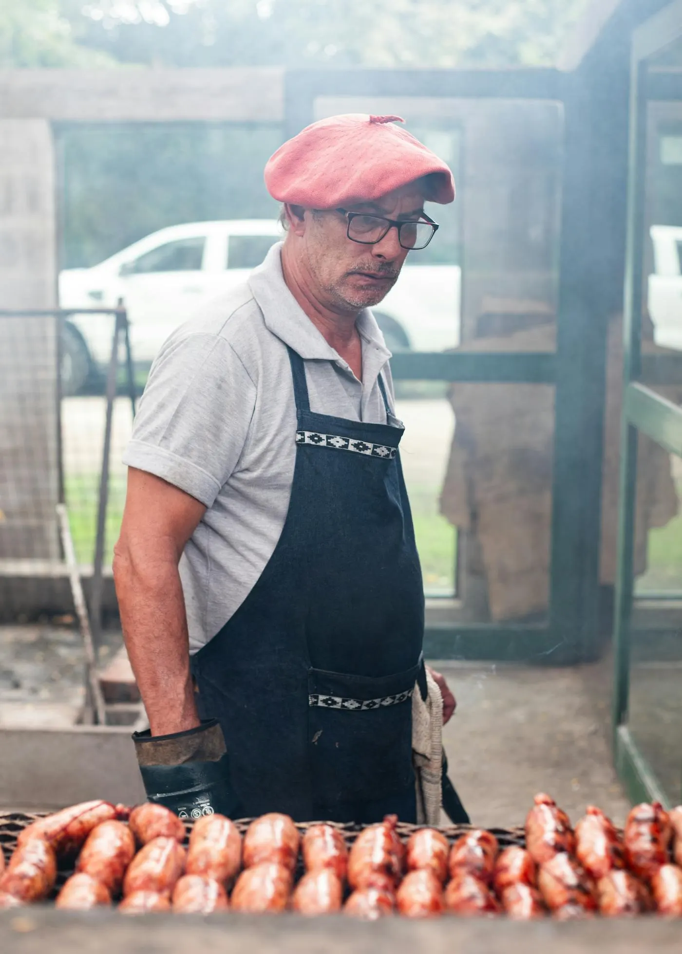 Parrillero grilling chorizo sausages on an Argentine asado at a Melbourne catering event